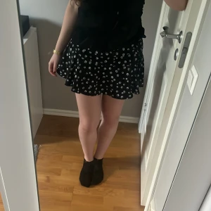 Blommig svart kjol - Super fin kort svart kjol med små vita blommor på. Den har inbyggda shorts, säljer då den inte kommer till användning 