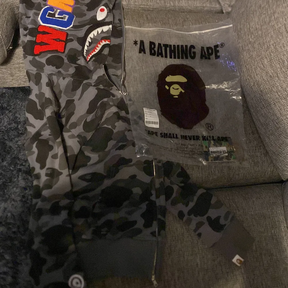 Hej, hoodien är inte äkta men ser exakt ut som äkta man får med en zip påse och lappen från bape med. Den är i bra skick men lite sönder med drag kedjan men det märker man inte av. Skriv om ni har frågor, pris går o diskutera. Hoodies.