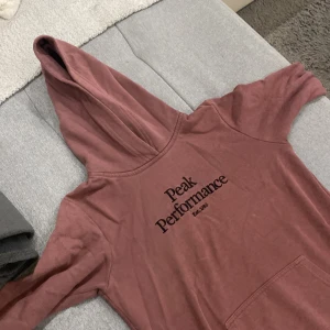 Peak performance hoodie strl 160 vinröd/lila - Gott skick, inga hål bara lite sleten eftersom den legat i garderoben men strykning innan leverans kommer utföras. Super skön att ha på sig.