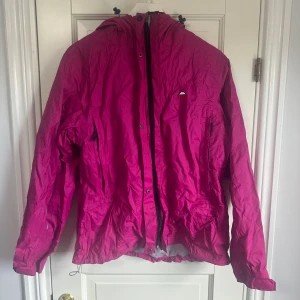 Rosa regnjacka - Ceriserosa regnjacka med huva från McKinley i storlek 40, fickor med dragkedja framtill. Jackan är använd ett fåtal gånger så i gott skick.q