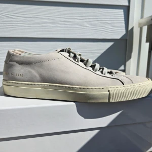 Grå sneakers från Common Projects - Säljer ett par stilrena grå sneakers från Common Projects. De är i nubuck och är storlek 44, skulle säga att de är åt det större hållet. Gjorda i Italien. Använda några gånger men i fint skick Låda och dustbag skickas med