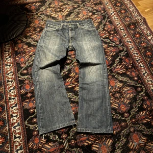 Levis bootcut jeans - Snygga blå jeansbyxor med klassisk design och knappgylf. De har en rak passform och är perfekta för en avslappnad stil. Jeansen har en lätt tvättad look som ger dem en cool vintagekänsla.