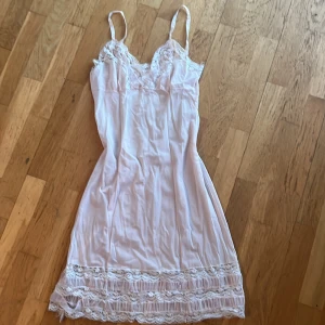 Rosa nattlinne med vita spetsdetaljer - Säljer ett elegant rosa nattlinne med vackra spetsdetaljer. Perfekt att sova med under de varma sommardagarna. Köptes på en secondhand butik och har ingen lapp. Lite sönder längst ner vid spetsdelen. Säljer för den inte har kommit till användning. 😁(pris går att diskutera)