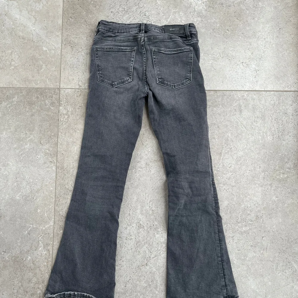 Snygga grå bootcut jeans med klassisk femficksdesign och knappgylf. Perfekta för en avslappnad stil med en touch av retro. De har en lätt tvättad look som ger dem en cool edge.. Farkut & Housut.