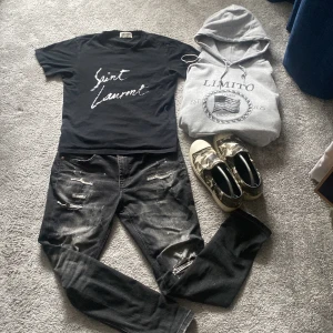 Svart t-shirt från Saint Laurent - Snygg svart t-shirt från Saint Laurent med vit text på framsidan. Perfekt för en stilren look. Kortärmad och i en klassisk passform och såklart riktig