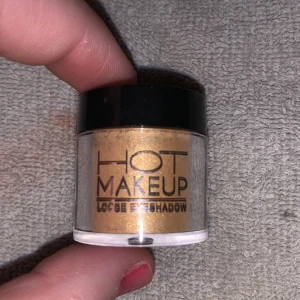 Guldögonskugga från Hot Makeup. Helt ny - Säljer en lös ögonskugga i en glittrande guldnyans från Hot Makeup. Perfekt för att skapa en glamorös look med intensiv färg och skimmer. Kommer i en praktisk burk med svart lock.