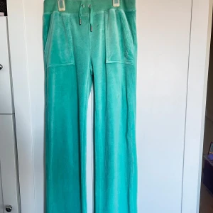 Turkos blå  juicy couture set - Snygga turkosa Juicy byxor  med matchande hoodie. Byxorna har en loose passform med snörning i midjan och praktiska fickor både fram och bak. Hoodien har dragkedja och en bekväm huva. Perfekt för en avslappnad stil.