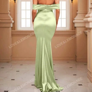 Ljusgrön axelbandslös långklänning från Love&Lemonade på tredje bilden så ser ni klänningen på men i vin rött - Elegant ljusgrön långklänning i satin från Love&Lemonade. Klänningen har en axelbandslös design med en vacker drapering över axeln och en figurnära passform som övergår i en svepande kjol. Perfekt för en glamorös kväll!