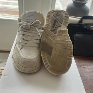 Vita sneakers från Axel Arigato - Snygga vita sneakers från Axel Arigato med en stilren design. Skorna har snörning och en robust sula med märkets logotyp. Tillverkade i en kombination av skinn och mocka för en trendig look. Använda men bra skick. Nypris runt 3000 mitt pris 1850