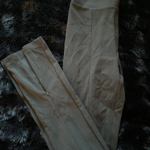 Svarta byxor med slits - Snygga svarta byxor med hög midja och slits vid anklarna. Perfekta för en stilren look. De har en tight passform som framhäver benen.