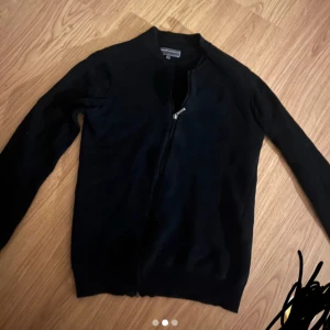 Svart kofta med dragkedja - Snygg svart kofta med dragkedja framtill. Perfekt för lager-på-lager under kyligare dagar. Enkel och stilren design som passar till det mesta.