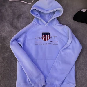 Ljusblå hoodie från GANT - Säljer en ljusblå Gant hoodie, den är i väldigt bra skick men den är andvänd fåtal gånger. Jag har tröttnat på den och det finns säkert någon som får mer användning av den. 
