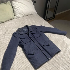 Riley Field jacket - Säljer en stilren mörkblå Fieldjacket från Riley, jackan har en rak passform och är perfekt för höst och vår men även vinterdagar som ej är så kalla. Modellen är 180cm. Pris kan diskuteras men skriv gärna vid svar av frågor!    // Elis