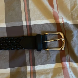 Svart flätat bälte med silverfärgat spänne - Priset kan diskuteras vid snabb affär. Snyggt svart flätat bälte med ett stilrent silverfärgat spänne. Perfekt för att ge en extra touch till din outfit. Bältet är tillverkat i skinn och har en klassisk design som passar till många olika stilar.