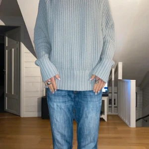 Grå stickad tröja - Säljer en mysig grå stickad tröja med lång ärm och ribbade detaljer vid ärmslut och nederkant. Perfekt för kyligare dagar. Passar bra till jeans eller andra avslappnade outfits.