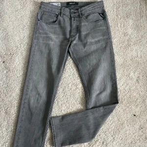 Grå jeans från Replay - Snygga grå jeans från Replay med en klassisk femficksdesign. De har en stilren look med en diskret logga på bakfickan. Perfekta för en avslappnad stil.