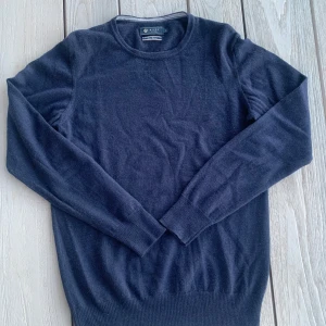 Merinoull tröja från Riley - Säljer en stilren mörkblå tröja från Riley i fin merinoull. Tröjan har en klassisk rund hals och långa ärmar, perfekt för kyligare dagar. Passar både till vardags och mer uppklädda tillfällen.                   Passform: passar de som vanligtvis har small