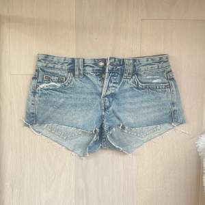 Säljer ett par snygga jeansshorts i en klassisk blå färg. De har en fransig kant och en lågmidjad passform. Perfekta för sommaren och festivaler! 🕶️