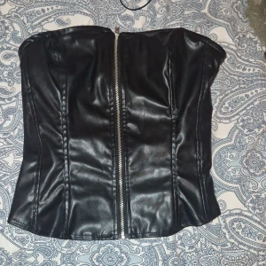 Svart läder korset topp - Jättefin svart korset topp med öppen rygg och silver dragkedja på framsidan.