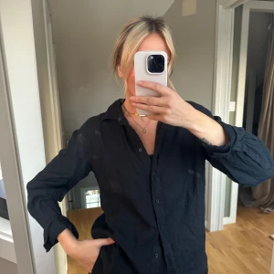 Svart långärmad skjorta - Säljer en stilren svart långärmad linneskjorta . Den har en klassisk krage och knappar längs framsidan. Perfekt för både vardag och festliga tillfällen. Passar bra till både jeans och kostymbyxor!