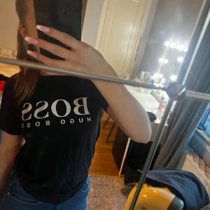 Svart t-shirt från Hugo Boss - Säljer en snygg svart t-shirt från Hugo Boss. Den har en klassisk passform och är perfekt för vardagsbruk. T-shirten är i bomull och har korta ärmar. Perfekt för en stilren look!