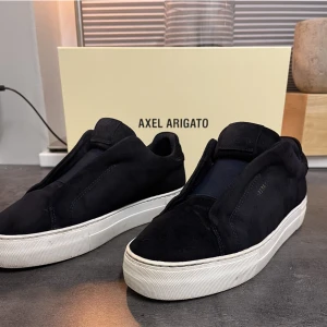 Axel Arigato skor  - Ett par navy Arigato skor i mocka-  modell Clean 360 Laceless, ser svarta ut. Mycket bra skick, storlek 42. Extra sulor, originalkartong och skopåse ingår.