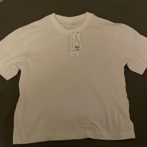 Vit t-shirt från H&M - Säljer en klassisk vit t-shirt från Gina tricot i storlek M. Den är helt ny med prislappen kvar. Perfekt basplagg för alla tillfällen. Gjord i mjukt bomullsmaterial för en bekväm passform.