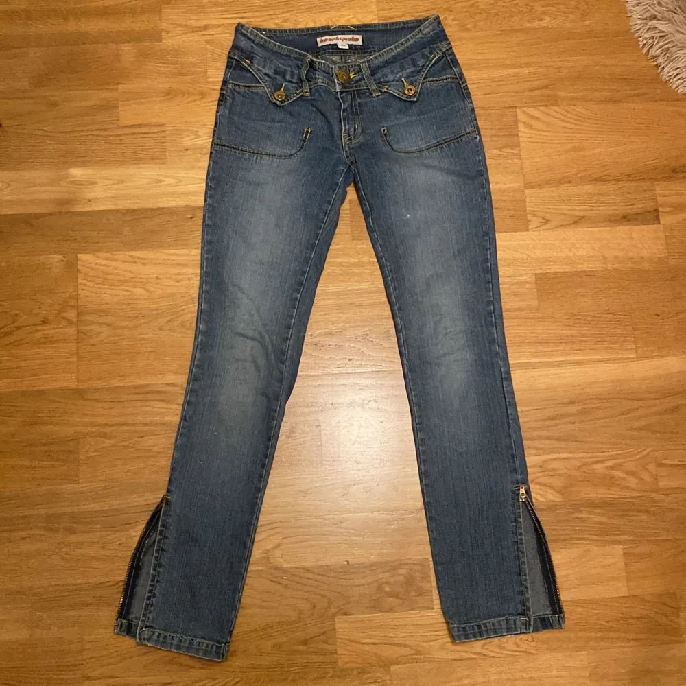 Jättecoola lågmidjade jeans‼️De har vackra detaljer vid fram och bakfickorna samt dragkedjor längst ner 🙏Köpta second hand därför lite slitna på vissa ställen (se sista bilden tex) priset är diskuterbart 💗 kontakta mig gärna vid frågor eller mått! 🍁. Jeans & Byxor.