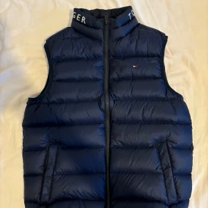 Tommy Hilfiger Väst - Hej!, Jag säljer min väst jag köpt från Tommy Hilfiger. Säljs på grund av att den blivit för liten och är i storlek 164.  Den är i nyskick samt har använts 2 gånger. Pris kan diskuteras. Finns att hämta i Järvastaden🤝. Nypris: 999kr Mitt pris:349kr