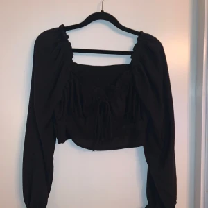 Svart långärmad topp med knyt - Säljer en snygg svart topp med långa ärmar och knytning framtill. Från Shein i storlek S. Aldrig använd 