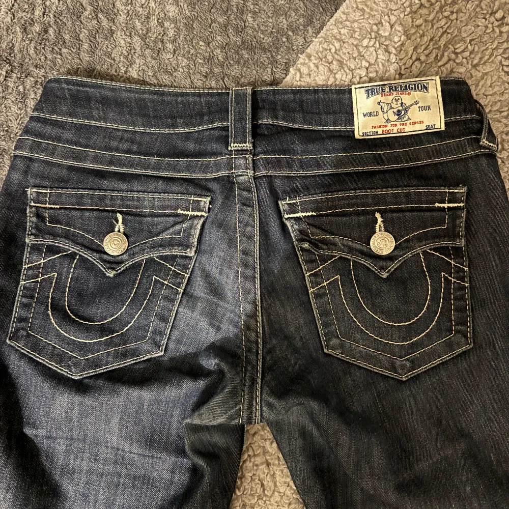 Säljer ett par snygga lowwaist bootcut jeans från true religion❤️midjemått: 37cm innerbenslägnden: 80cm.  Dragkedjan är lite krånglig och dom var uppsydda innan så en liten linje längst ner. Syns knappt! Annars bra skick❤️ skriv privat för frågor!❤️. Jeans & Byxor.