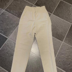 Beige kostymbyxor - Säljer ett par stilrena beige kostymbyxor från Zara. De är högmidjade och har en klassisk straight passform. Storlek XS
