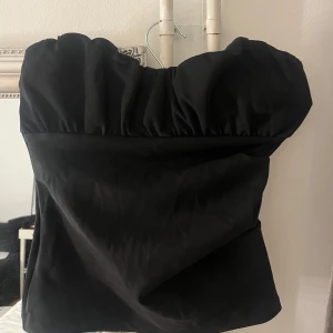 Svart tubtopp från Zara - Elegant svart tubtopp från Zara med en stilren design. Toppen är axelbandslös och har en smickrande passform som passar perfekt för festliga tillfällen. Även prislappen är på/ helt ny. Storlek S🫶