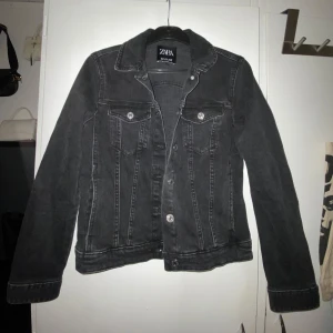 Svart jeansjacka från Zara - Svart/mörkgrå jeansjacka ifrån zara i storlek S. Bara använt fåtal gånger så väldigt bra skick fortfarande. Kroppsnära passform men inte för tajt heller.