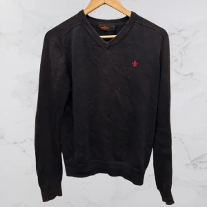 Mörkblå tröja från Morris - Säljer en stilren mörkblå tröja från Morris i 100% pima bomull. Tröjan har en v-ringad design och en liten broderad detalj på bröstet. Perfekt för en klassisk och bekväm look. Tröjan är lite solblekt därmed priset. Hör av er vid minsta fundering!