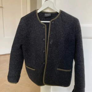 Mörkgrå ulljacka / kofta - Snygg mörkgrå ulljacka från Reine Schurwolle med gröna detaljer och knappar framtill. Fungerar både som kofta och jacka! Står ej storlek men passar en S❤️