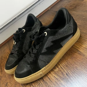 Svarta sneakers från Zadig & Voltaire - Svarta sneakers från Zadig & Voltaire med en blixtdetalj på sidan. Köpte dessa här på plick  men säljer dem eftersom de var för stora för mig.    Ny pris är runt 3000 kr, själv köpte jag dom för 1300 kr men säljer dom lite billigare på grund av skornas skick.