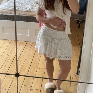 Vit spetskjol - Söt vit kortkjol i spets med volangdetaljer. Perfekt för sommarens varma dagar. Kjolen har en luftig och romantisk känsla.