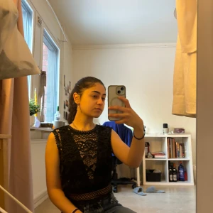 Svart spetslinne - Säljer ett snyggt svart spetslinne med detaljerad spetsdesign. Linnet är croppat och ärmlöst, perfekt för en trendig look. Passar bra till både jeans och kjol.