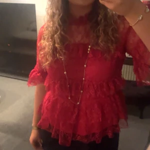 Röd spetsblus med volanger - Röd spetsblus med volanger. Använd endast en gång så i väldigt bra skick, kommer tyvärr inte till användning.