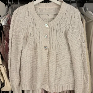 Vit stickad babydoll kofta  - Mysig beige stickad babydoll kofta från L.O.G.G. med dekorativa knappar och flätstickat mönster. Stl M men passar mer S 🌸😊