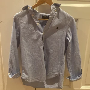 Blå polo Ralph lauren skjorta  - En blå Ralph lauren skjorta till salu för ett rimligt pris varför inte uppgradera din garderob till Max med denna blå skjorta den har inga fläckar eller är inte sönder 9,5-10 i skick😎