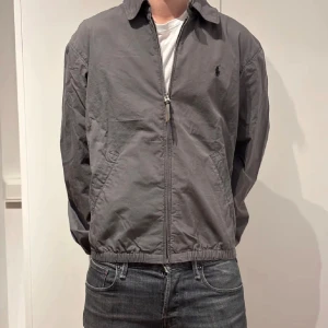 Grå jacka från Polo Ralph Lauren - Säljer en stilren grå jacka från Polo Ralph Lauren.  Perfekt för våren. Jackan är i bra skick, är knappast använd.