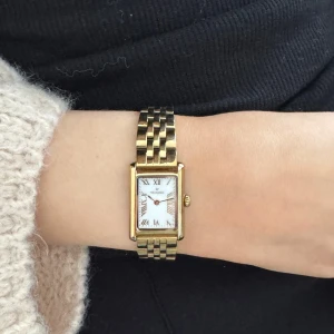 Elegant guldfärgad klocka - Snygg guldfärgad klocka med rektangulär urtavla och romerska siffror. Armbandet är i metall med en klassisk länkdesign. Perfekt för att ge en touch av elegans till din stil.  Obs den har lite små repor men inget som syns om du inte tittar nära 