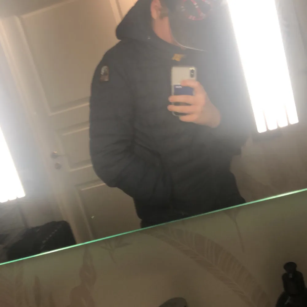 Säljer en svart dunjacka från Parajumpers med huva och dragkedja. Jackan har ett märke på ärmen och är perfekt för kyligare väder. Den är stilren och funktionell med en quiltad design.. Takit.