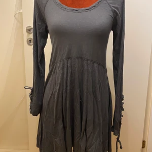 Grå klänning med snörning melmelli S - Snygg grå klänning med långa ärmar och cool snörningsdetalj på ärmarna. Perfekt för en stilren look.  Ny och oanvänd Längd: 83 cm Armhåla till armhåla: 38 cm Lika blandning av bomull och Tencel.  Inga bilder när den sitter på mig! Katter finns i hemmet