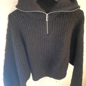 Svart stickad tröja med dragkedja - Mysig svart stickad tröja med dragkedja fram. Från Gina. 