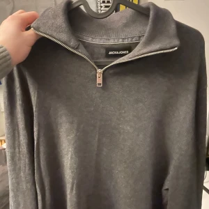 Grå tröja med dragkedja från Jack & Jones - Snygg grå tröja från Jack & Jones med dragkedja vid halsen. Perfekt för kyligare dagar med sin stilrena design och bekväma passform. Nypris 500 skick 9,5/10