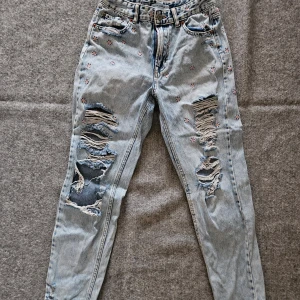 Slitna jeans med blommor från Pull & Bear - Slitna jeans med blommor broderade på dem. Skick enligt bilder. Storlek 36.