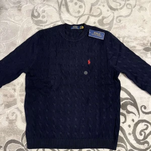 Mörkblå stickad tröja från Polo Ralph Lauren - Snygg mörkblå stickad tröja från Polo Ralph Lauren. Helt ny och aldrig använd, så det finns inga fel med den.